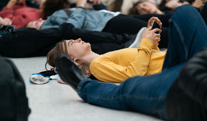 A young man in a yellow jumper lays down on the fllor amongst other disabled activists