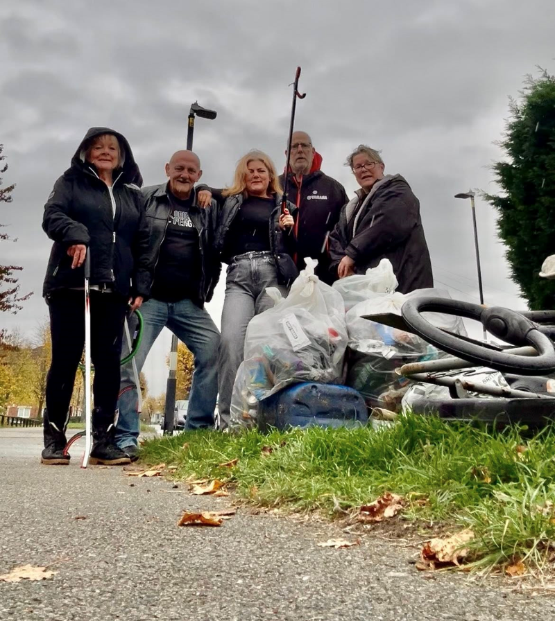 Five male and female neighbourhood litter pickers pose for a group photo with a pile of rubbish they have collected on the ground in front of them. They are the Friends of Stockingford (Nuneaton).