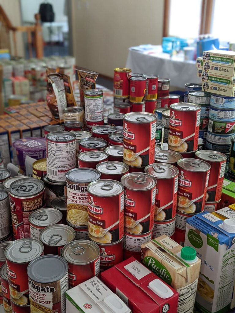 This image shows cans of food donated and piled up ready at a food bank.