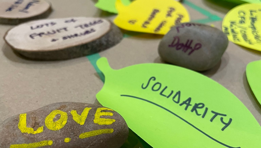 Post it, pebbles and slices of natural wood spread out on a floor with messages and ideas written on them from Feburary 2023's Collaboration Station.