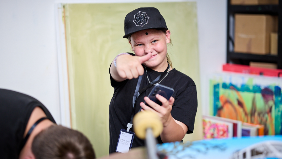 Photo by Andy Moore shows a young white girl in a black baseball cap at an exhibition giving a thumbs up for the camera.