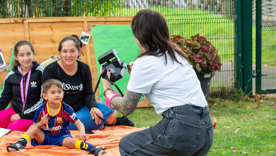 A woman in jeans takes a photo of a family at the BBQ using an instant camera