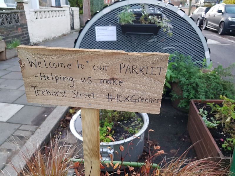 A handmade parklet sign welcomes people to the parklet with planters sat behind it. Credit: Hackney Council