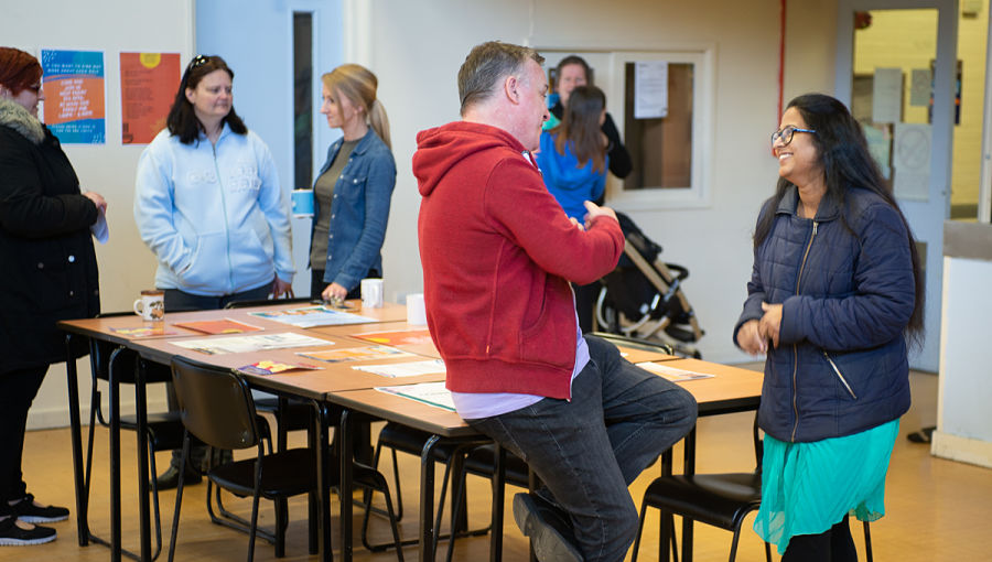 A group of people and professional gather to chat around a table in Willenhall