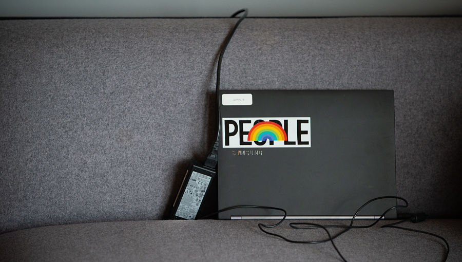 Laptop on a sofa with a sticker saying the word People on it