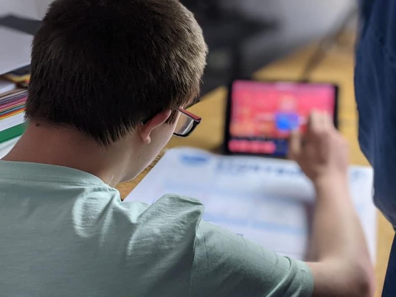 A young man in galsses works with an art pad and tablet to produce a stop motion animation