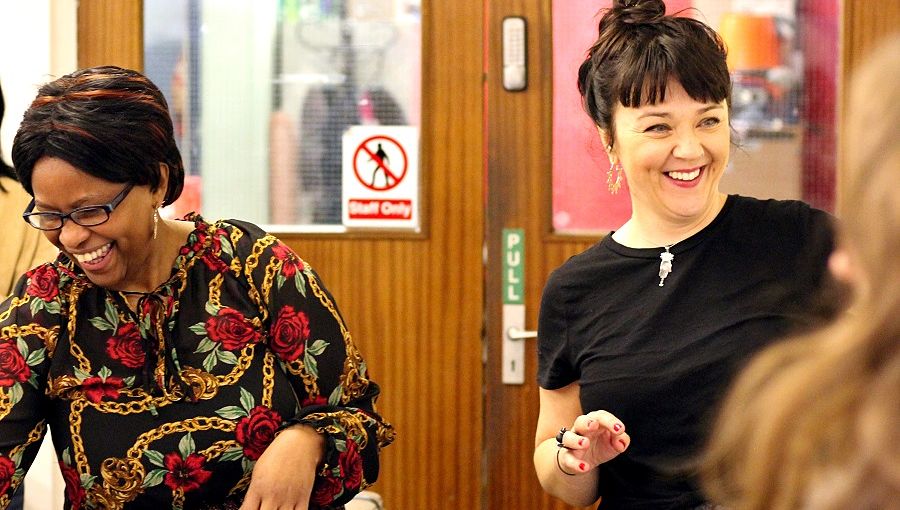 Two women, one black and one white, laugh as they engage with local people inside a community centre in Coventry. They are both Grapevine community organisers.