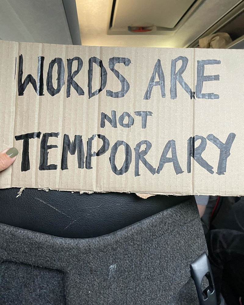 A cardboard placard reads Words are not temporary